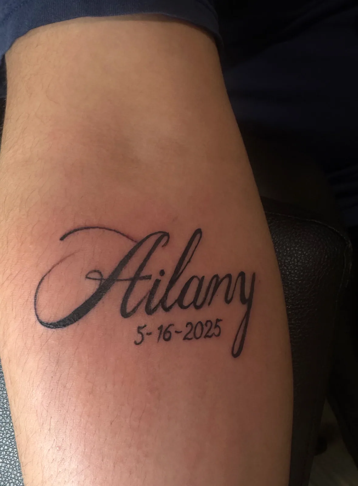 Fine-line script name tattoo with dated lettering on the inner forearm.