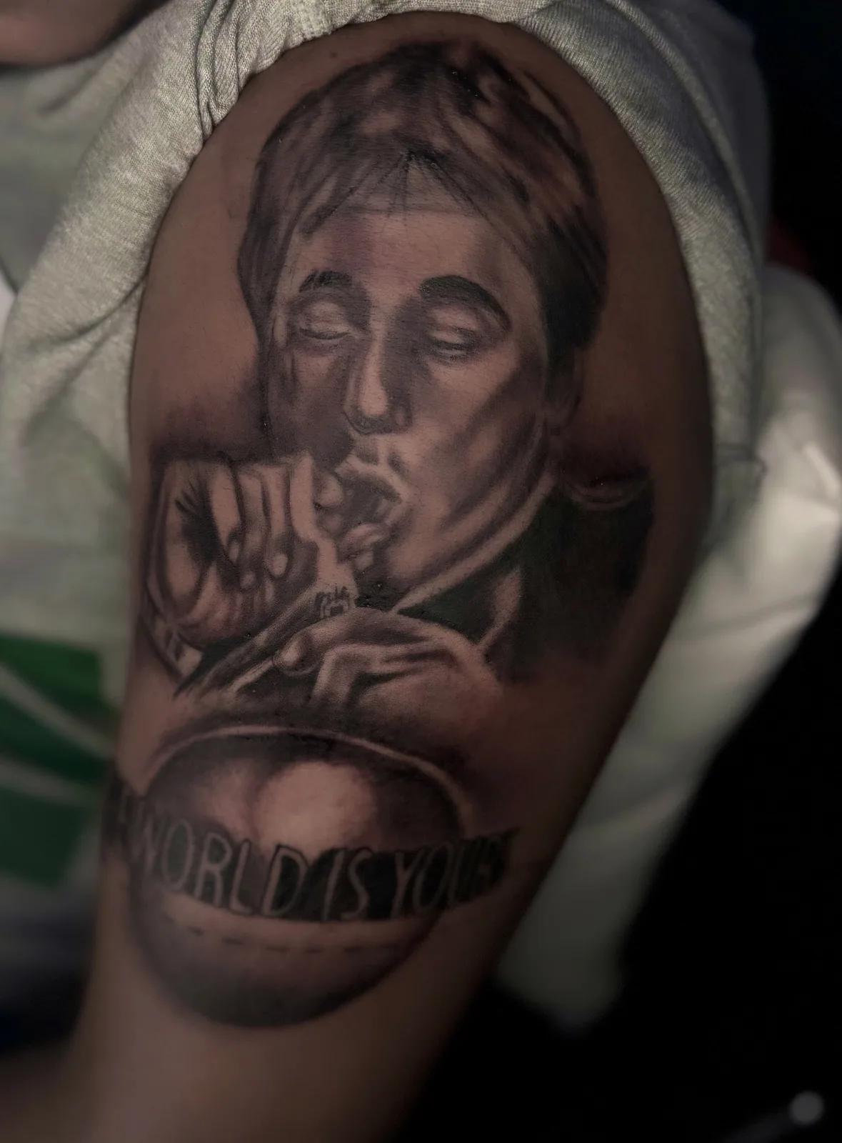 Black-and-grey realism portrait of a man smoking with banner script on the upper arm.